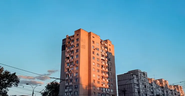 Blocuri de locuințe cu multe etaje, luminate de soare, pe cer albastru